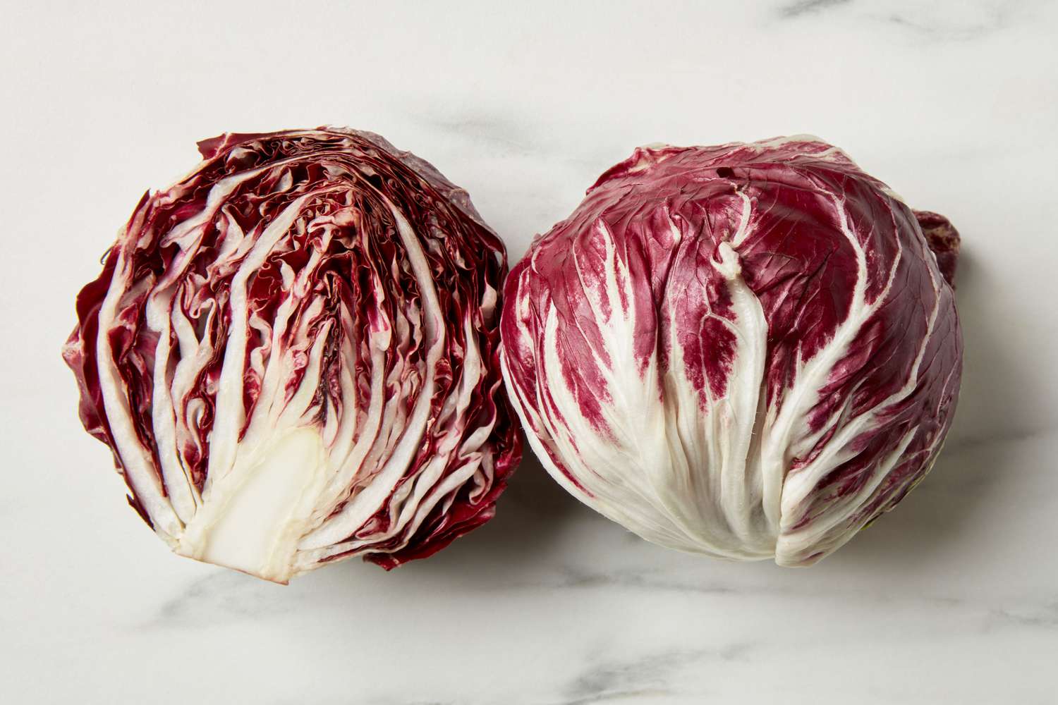 A head of radicchio, cut in half, on a marble surface