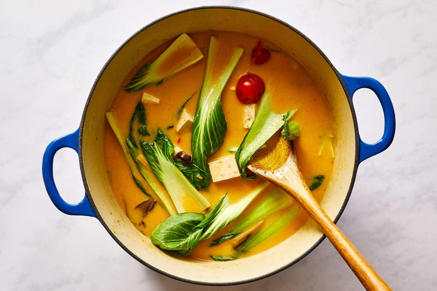 Vegetarian Tom Yum soup in a pot with a wooden spoon