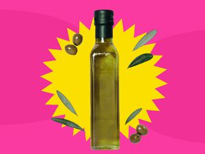 A bottle of olive oil with a yellow sunburst graphic behind it, all on a hot pink background