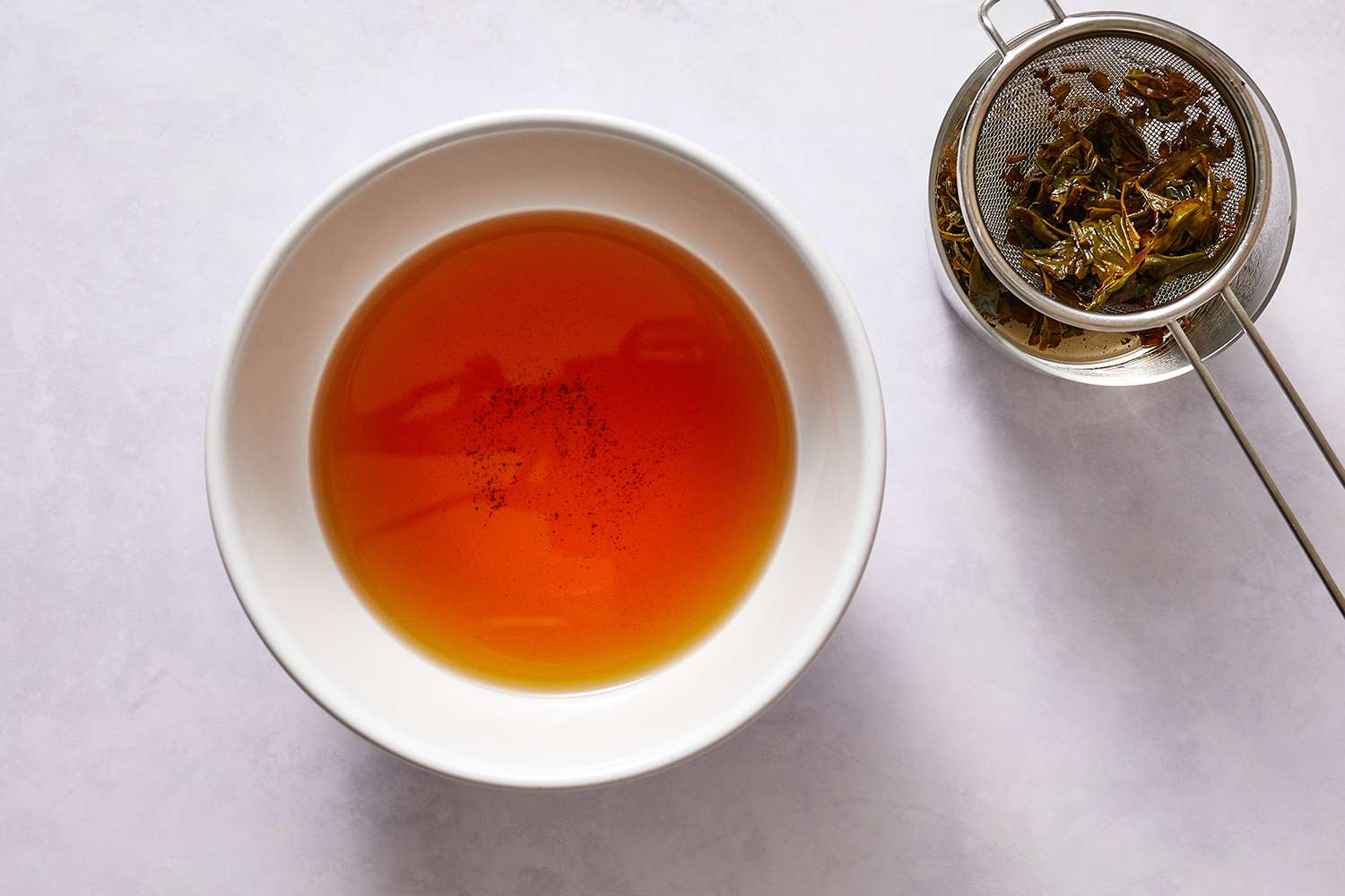 Seeped oolong tea in a bowl, with strained tea leaves on the side