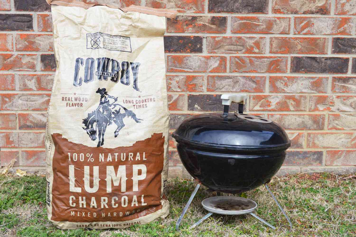 Cowboy Hardwood Lump Charcoal in a bag next to a small grill 