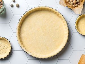 A tart pan lined with shortcrust pastry dough