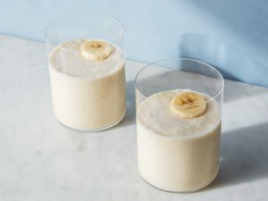 Two glasses of banana smoothies, garnished with sliced bananas