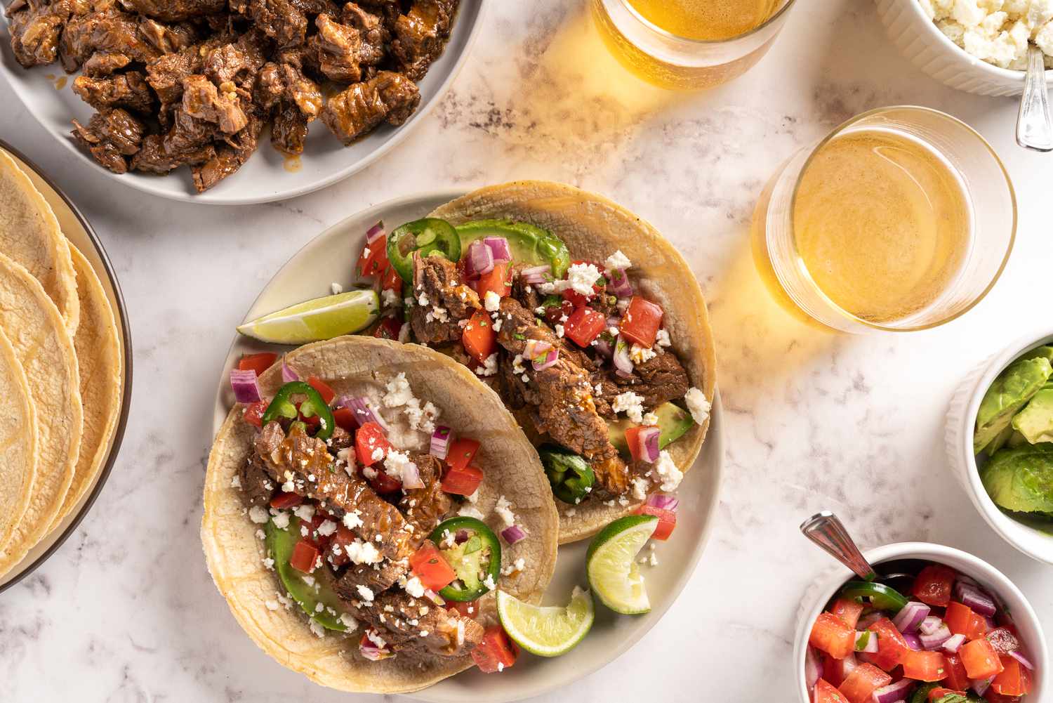 Carne asada in tortilla shells, served with lime wedges and other garnishes