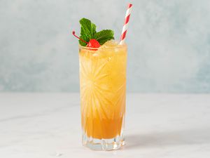 Yellow bird cocktail garnished with cherry and mint