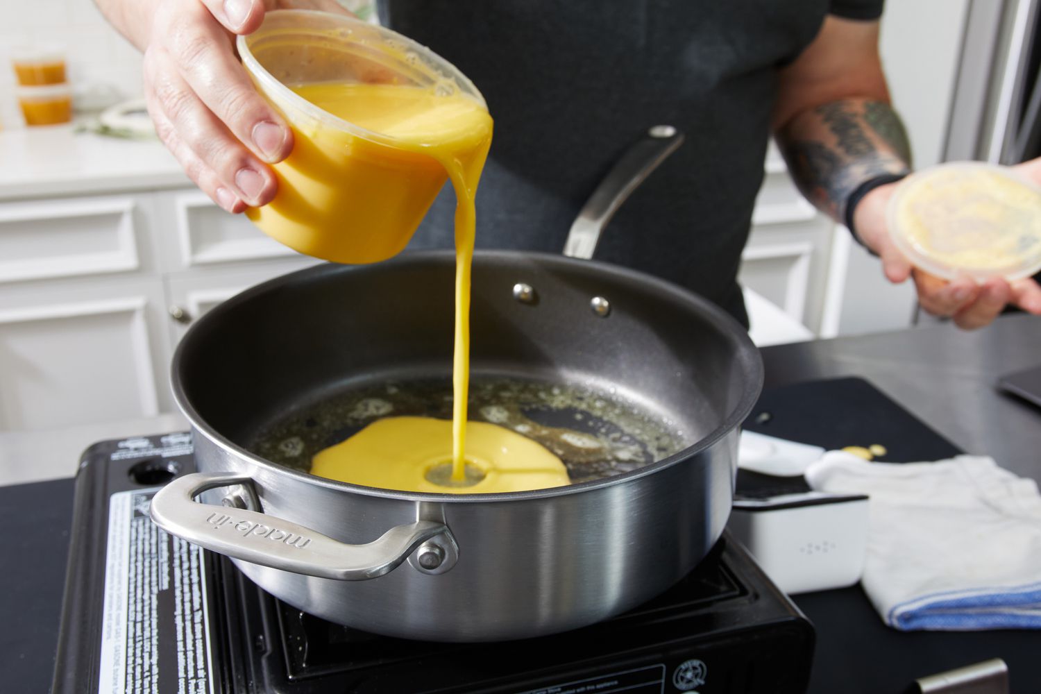 Person's hand pouring eggs from measuring cup into Made In 7-Piece The Non Stick Set saute pan