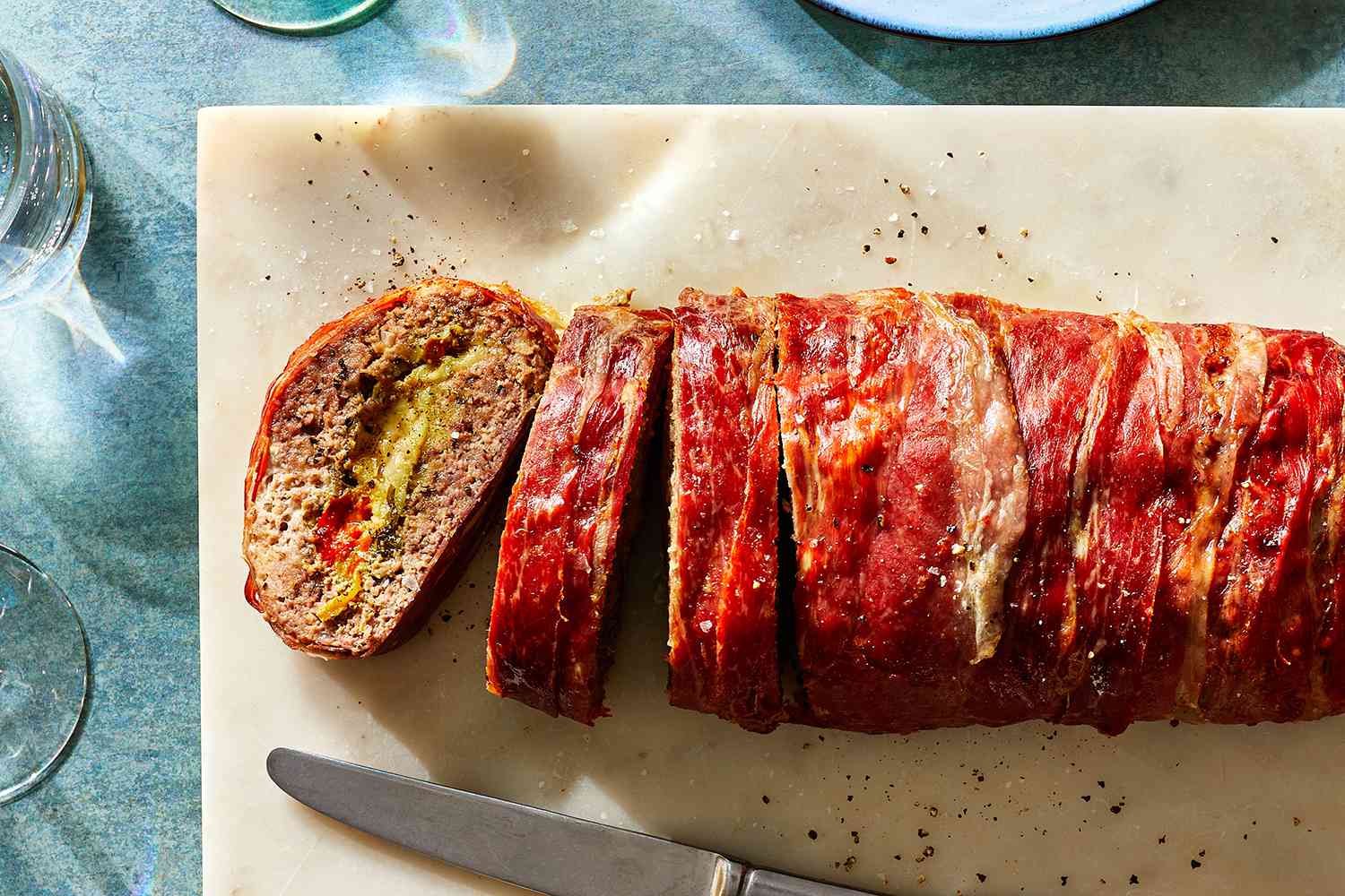 Prosciutto-Wrapped Stuffed Meatloaf sliced on a cutting board 