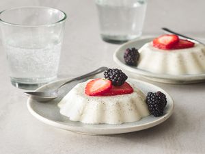 Two servings of vanilla panna cotta, stopped with sliced strawberries and blackberries