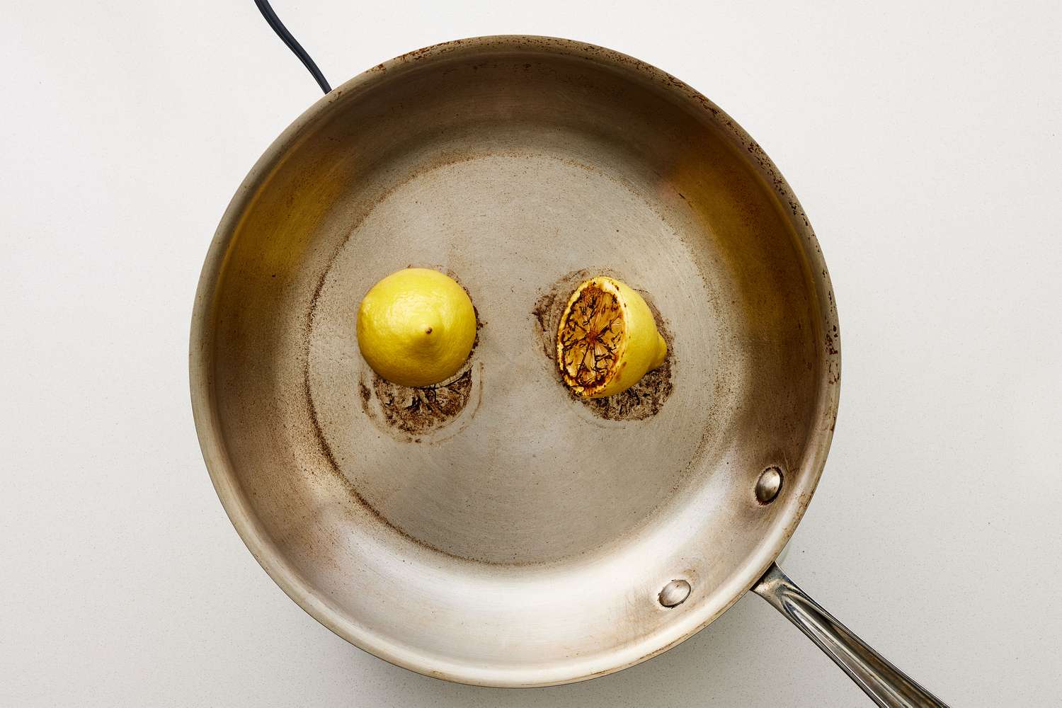 A small skillet with two charred lemon halves