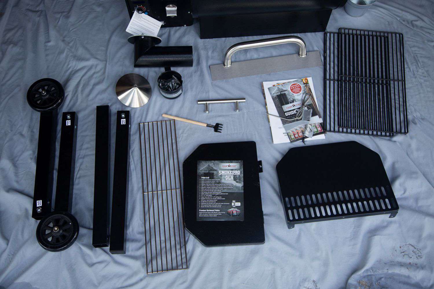 Parts of the Camp Chef SmokePro DLX Pellet Grill laid out on a sheet