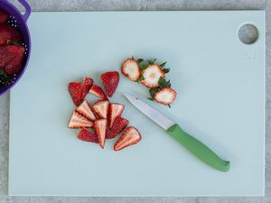 Sliced strawberries and a knife on Material The reBoard Cutting Board
