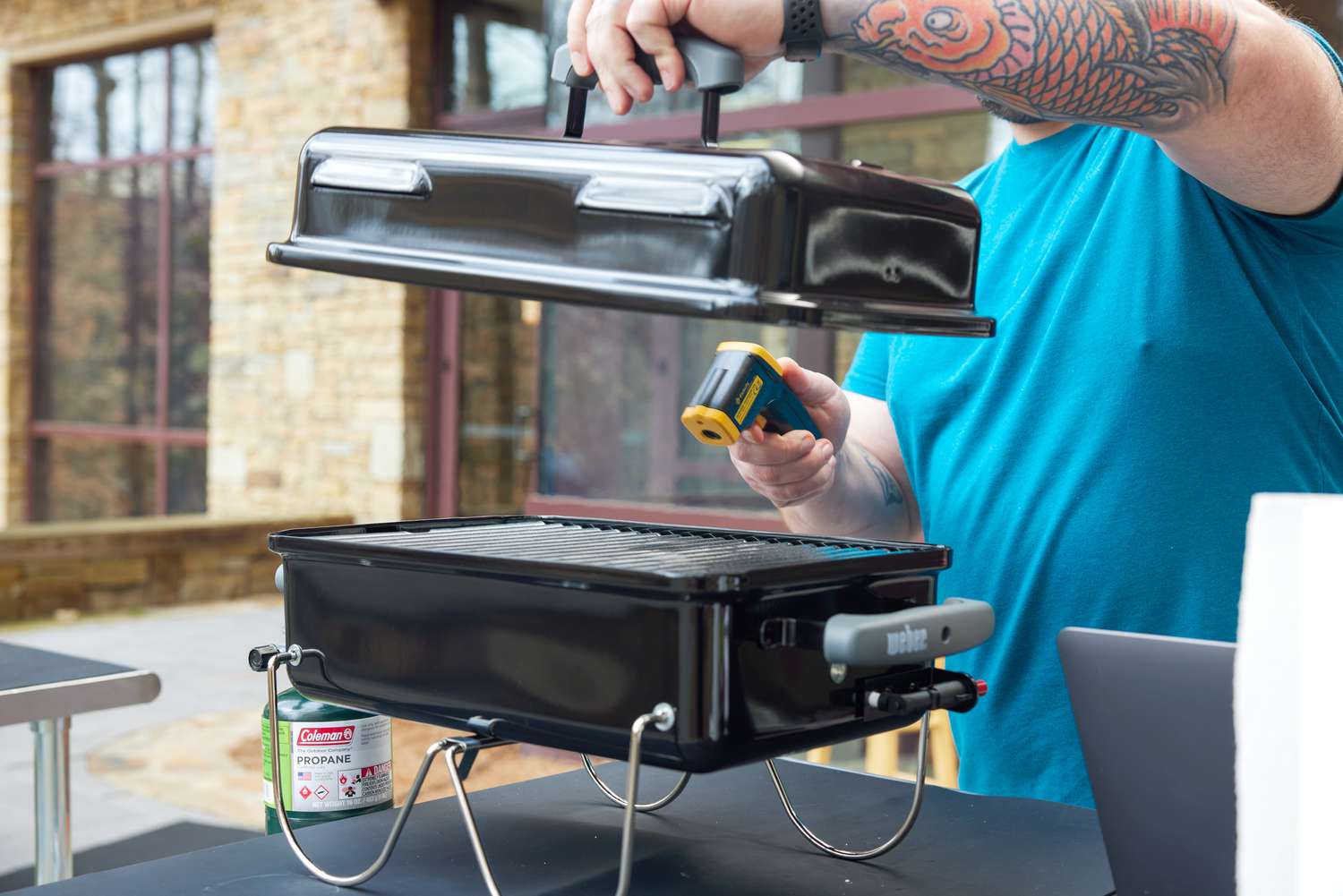 person checking the temperature of a Weber Go-Anywhere Charcoal Grill