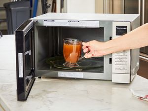 A glass of Kettle & Fire Bone Broth is placed in a microwave