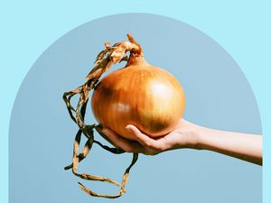 A hand holding a large onion