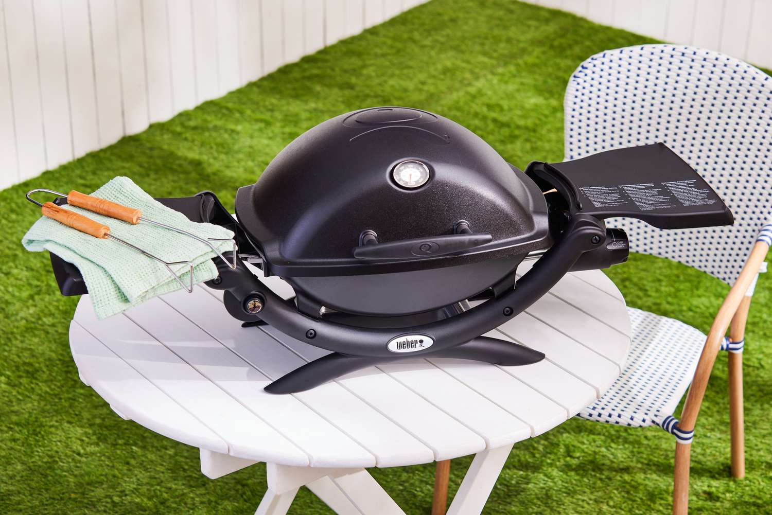 Weber Q1200 Gas Grill in a backyard table with green grass in the background