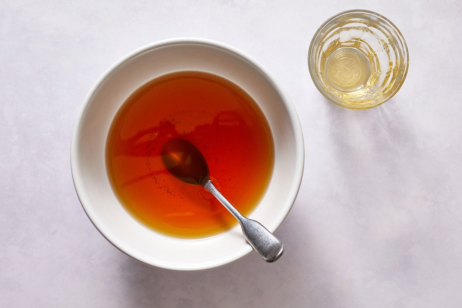 A spoon stirring honey into a bowl of tea