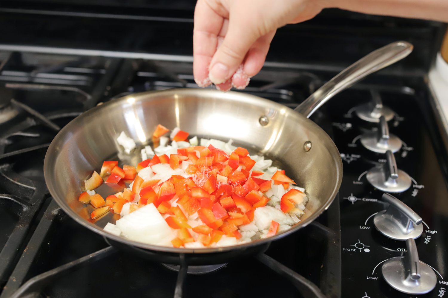 Adding vegetables in the All-Clad G5 frying pan on a gas stove