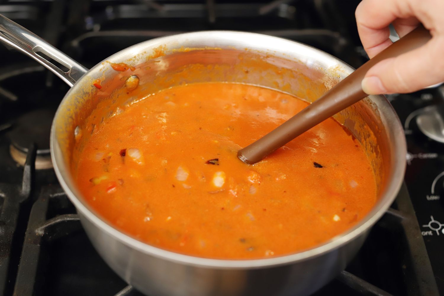 Hand stirring sauce in the All-Clad 2.5-Quart G5 Stainless Steel Saucier