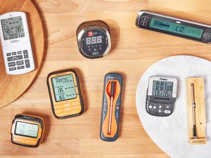 Eight various types of meat thermometers on a wooden surface