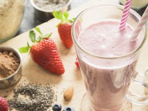 Strawberry milkshake with strawberries and almonds next to it