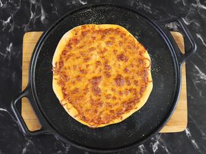 Cooked pizza displayed on a Lodge 14” Cast Iron Baking Pan