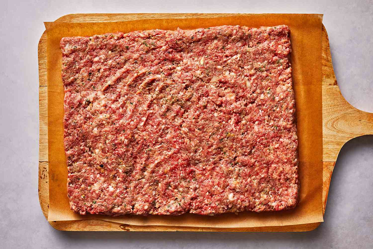 Large rectangle of the meat mixture on a parchment paper lined cutting board 