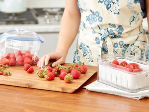 cutting strawberries and placing them into boxes 