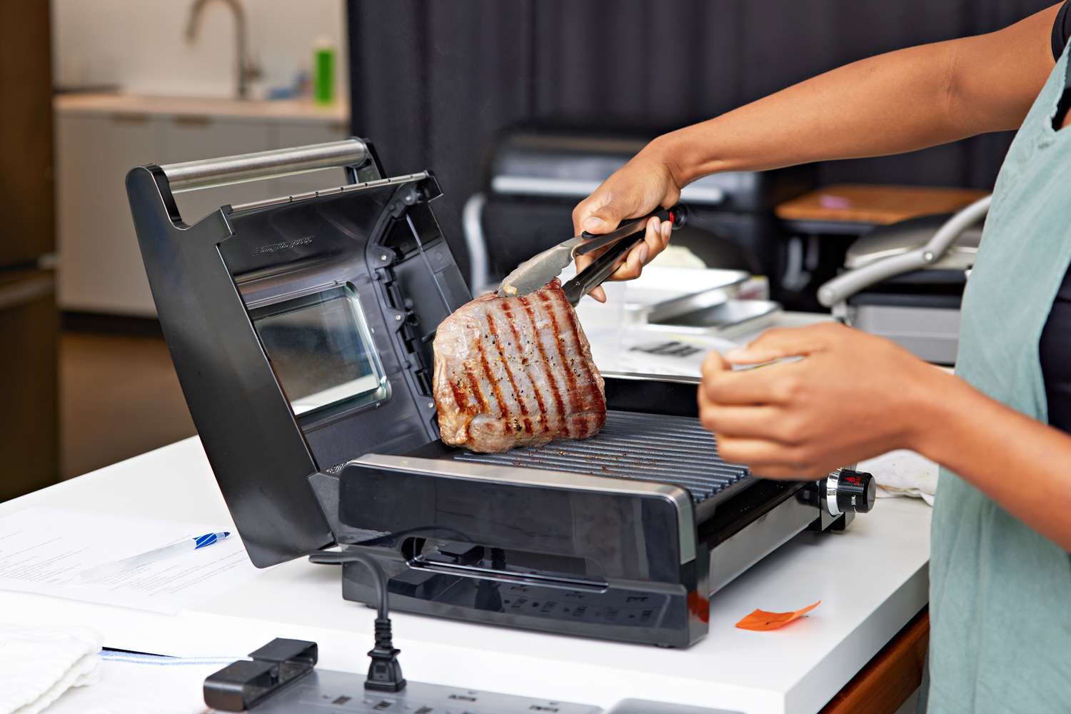 Person using tongs to flip steak on a Hamilton Beach 25361 Electric Indoor Searing Grill with Viewing Window