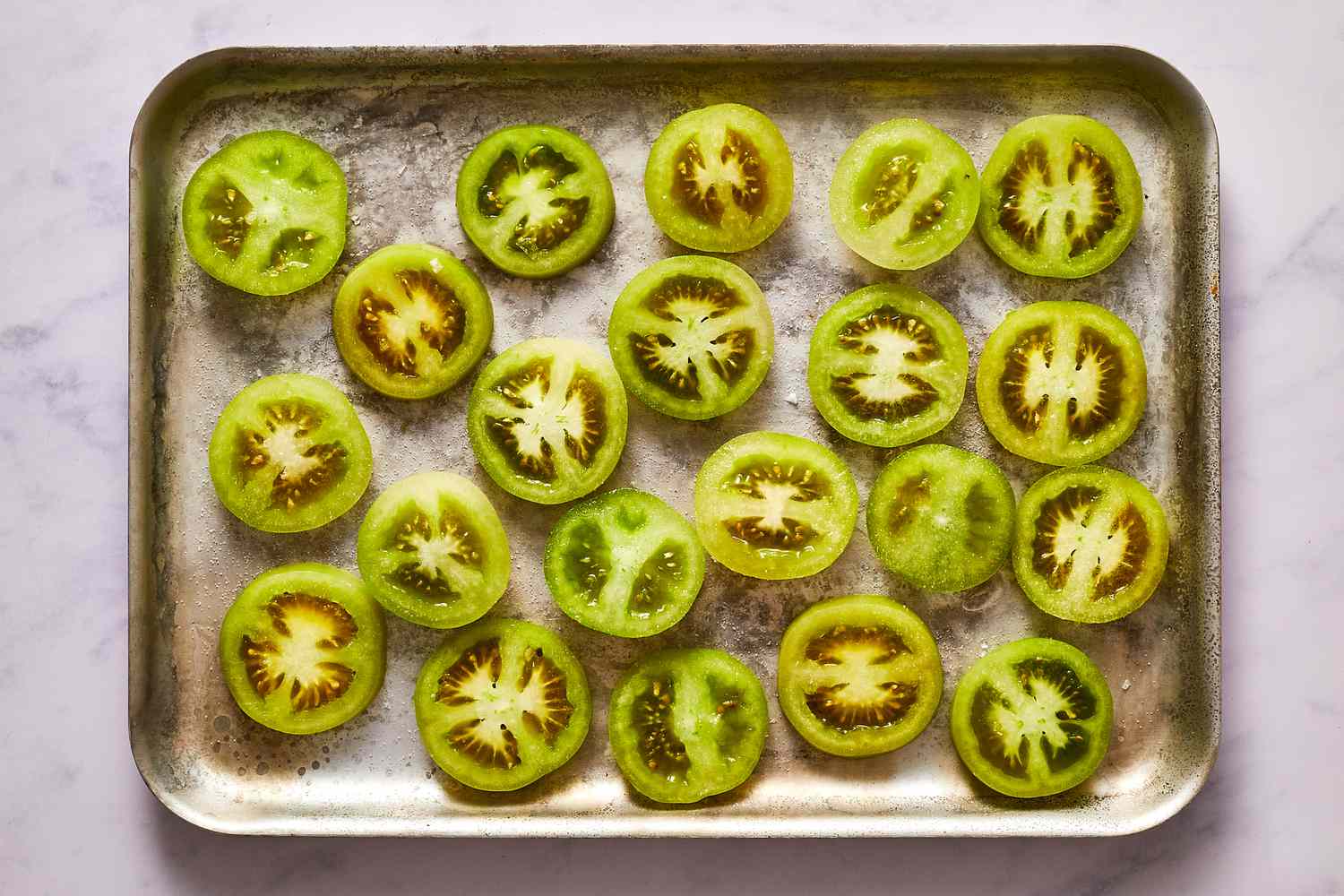 seasoned sliced green tomatoes on a baking sheet