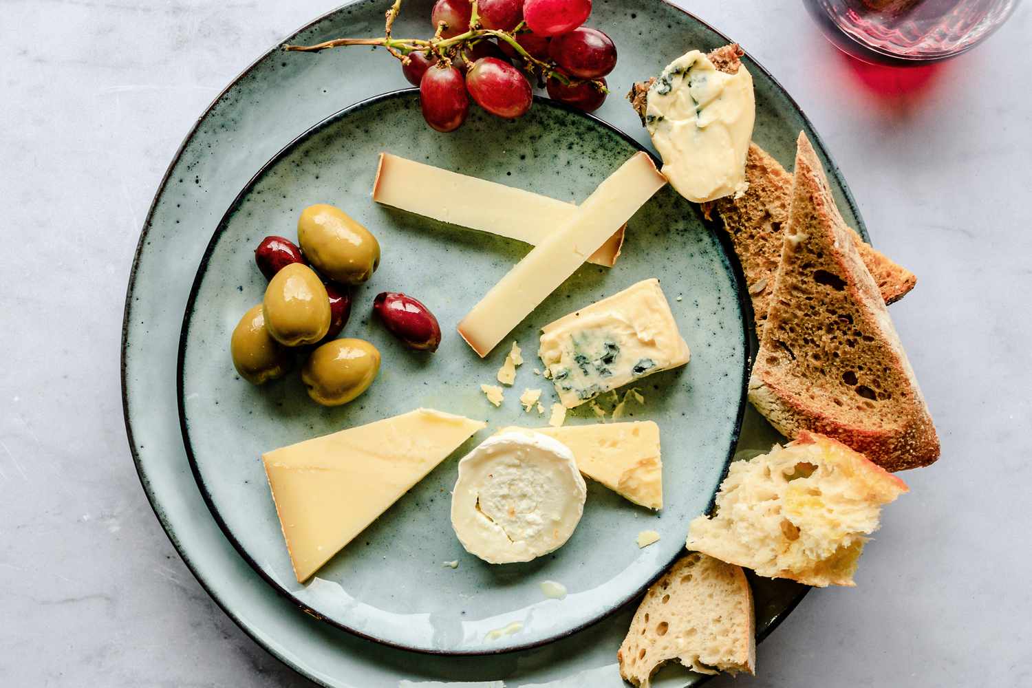 variety of cheeses with bread and olives on a plate