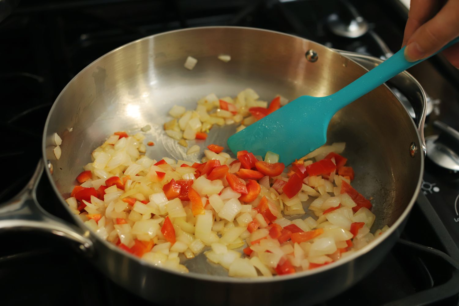 Person stirring food in pan of Caraway Stainless Steel Cookware Set