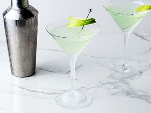 Green apple martini cocktails and a cocktail shaker on a marble table