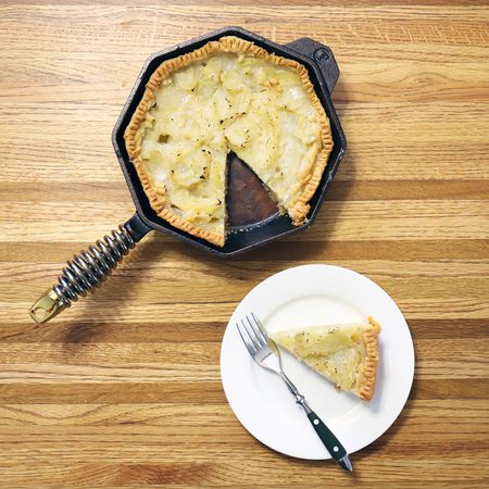 Finex Cast Iron Skillet displayed on butcher block counter with nearby white plate, piece of pie, and fork