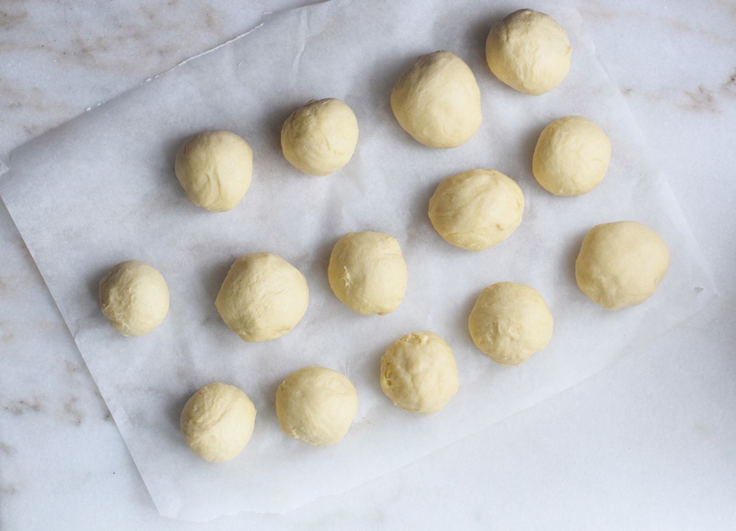 balls of dough rolled out onto a parchment paper