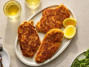 A platter with chicken Milanese, served with slices of lemon