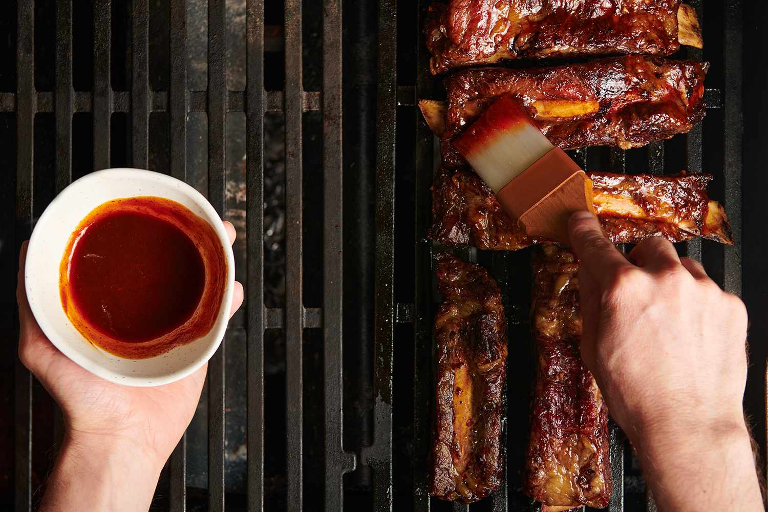 Beef ribs brushed with barbecue sauce on a grill