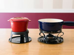 Two fondue pots displayed on a wooden table