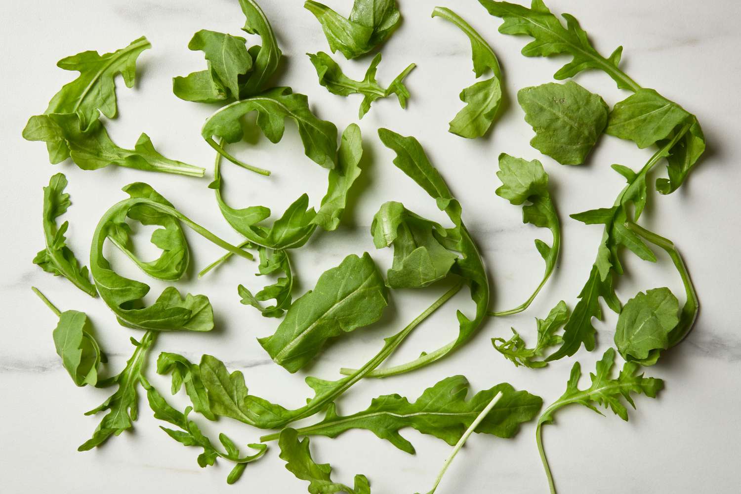 Leaves of arugula scattered on a marble surface