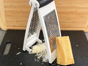 OXO Good Grips Multi Grater displayed on a cutting board next to a wedge of Parmigiano Reggiano