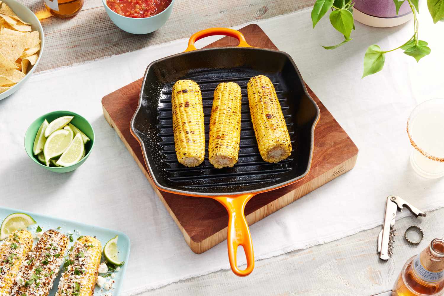 Grilled corn in the Le Creuset Square Skillet Grill Pan on a table surrounded by food. 