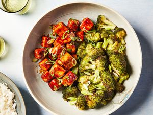 A large bowl of crispy teriyaki tofu garnished with thinly sliced scallions, served with broccoli and white