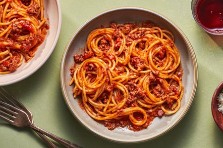 Two bowls of spaghetti bolognese served with red wine