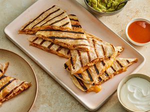 A platter of grilled honey chipotle chicken quesadillas, served with salsa, sour cream, and guacamole