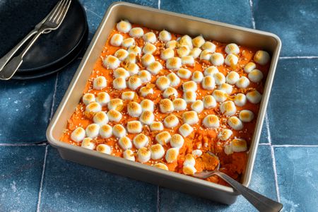 A miso sweet potato casserole in a square baking dish, topped with toasted marshmallows and sesame seeds