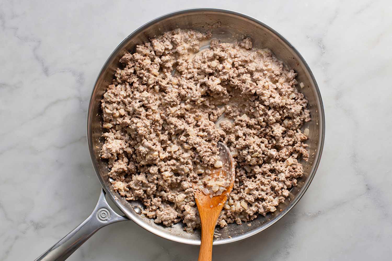 A skillet with ground beef, onion, and sauce mixture