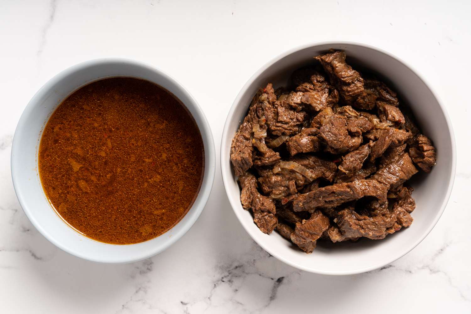 Drained carne asada in one bowl and cooking liquids in another bowl