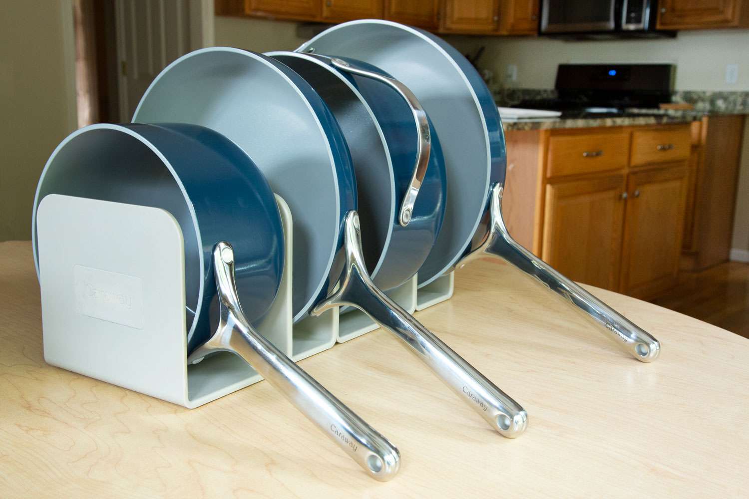 Caraway Cookware Set lined up in a pot holder on a wood table