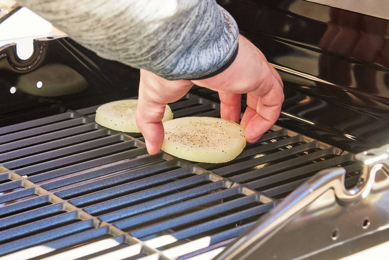 A person placing a vegetable on the Char-Broil Performance Series 2-Burner Gas Grill