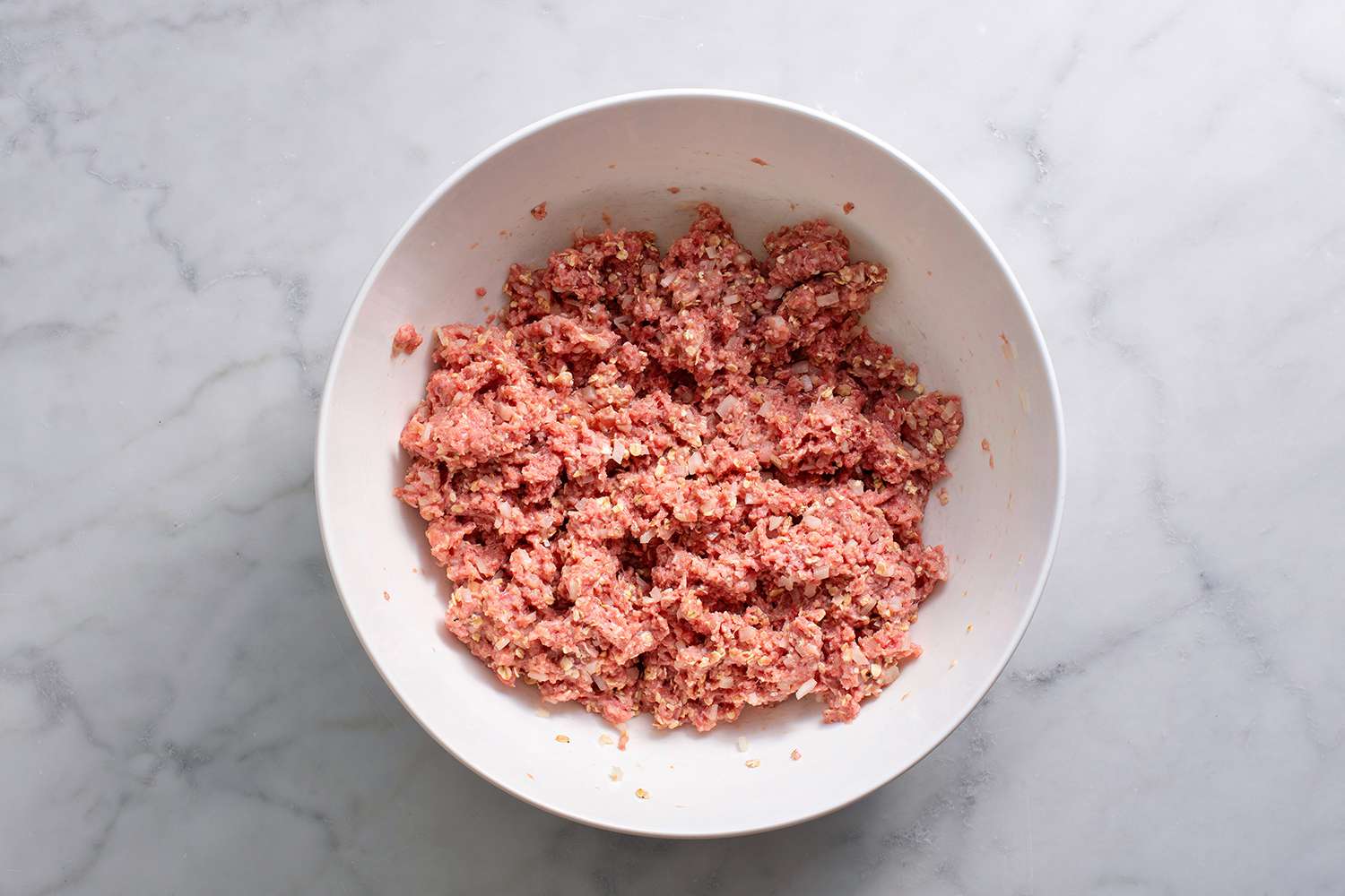 Ground beef, oats, onion, milk, eggs, and seasonings mixed in a large bowl
