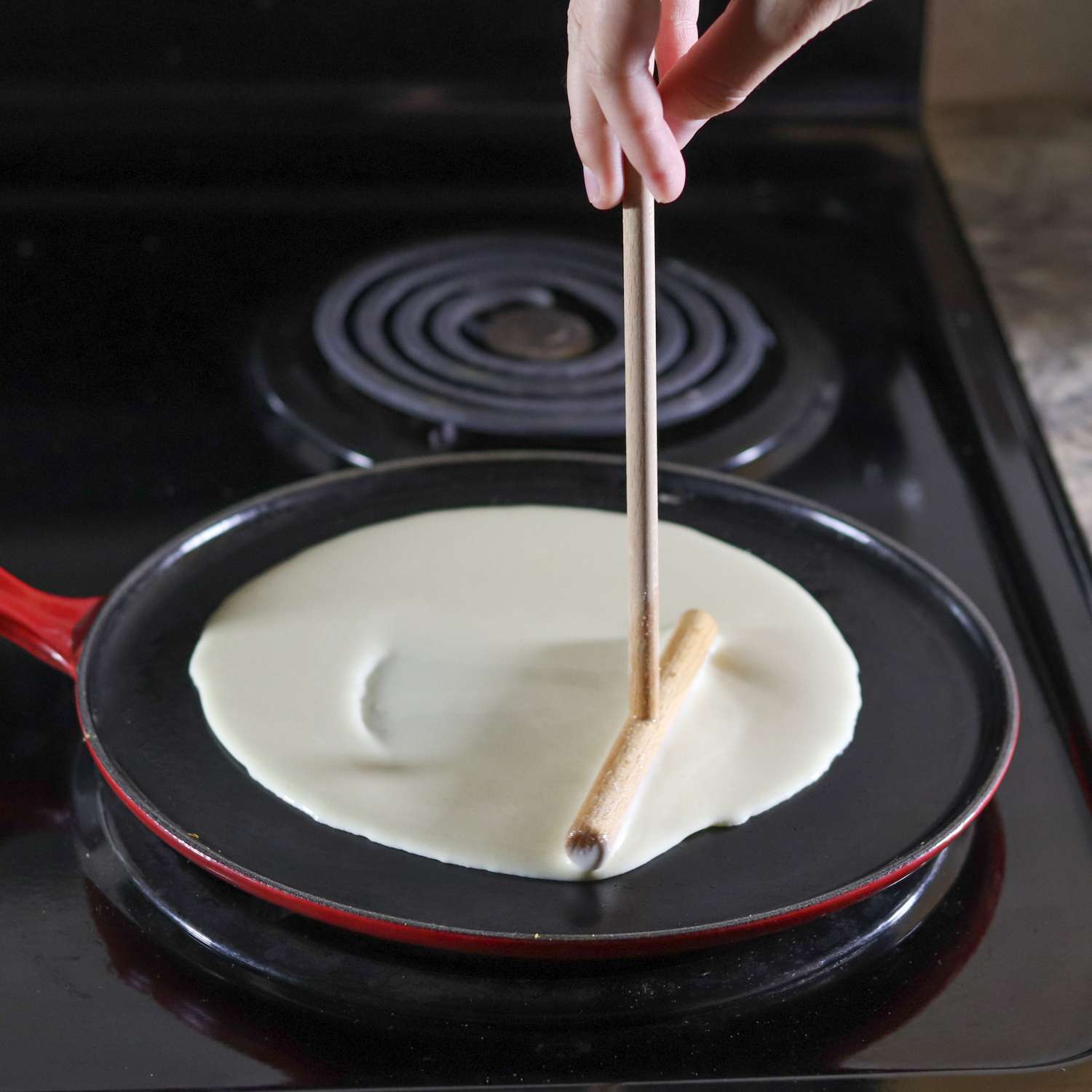 Hand spreading crepe batter on the Le Creuset Cast Iron Crepe Pan